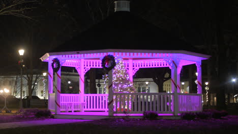 wooden gazebo illuminated by christmas lights with wreath at night