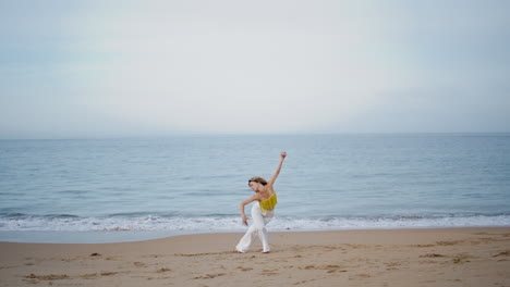 woman moving body gracefully on sand beach summer evening. curly girl dancing