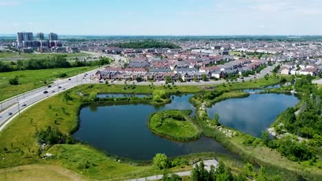 aerial view flying over sunny toronto neighborhood homes with a bright blue pond