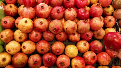 hand selecting pomegranate from market display