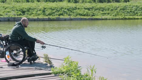 man with disabilities fishing at a lake. wheelchair. summertime. disabled person fishing