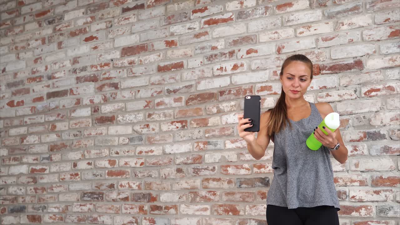 Woman taking selfie with water bottle at gym
