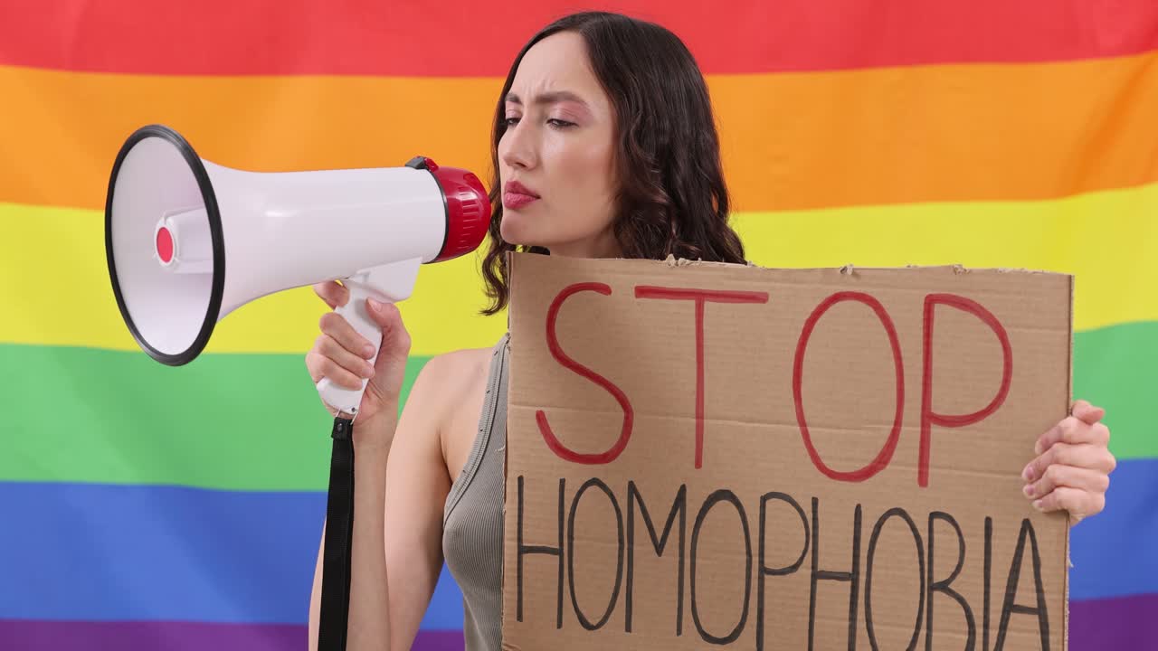 Donna che protesta contro l'omofobia con la bandiera arcobaleno LGBTQ
