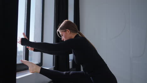 woman stretching in a yoga pose in front of a window