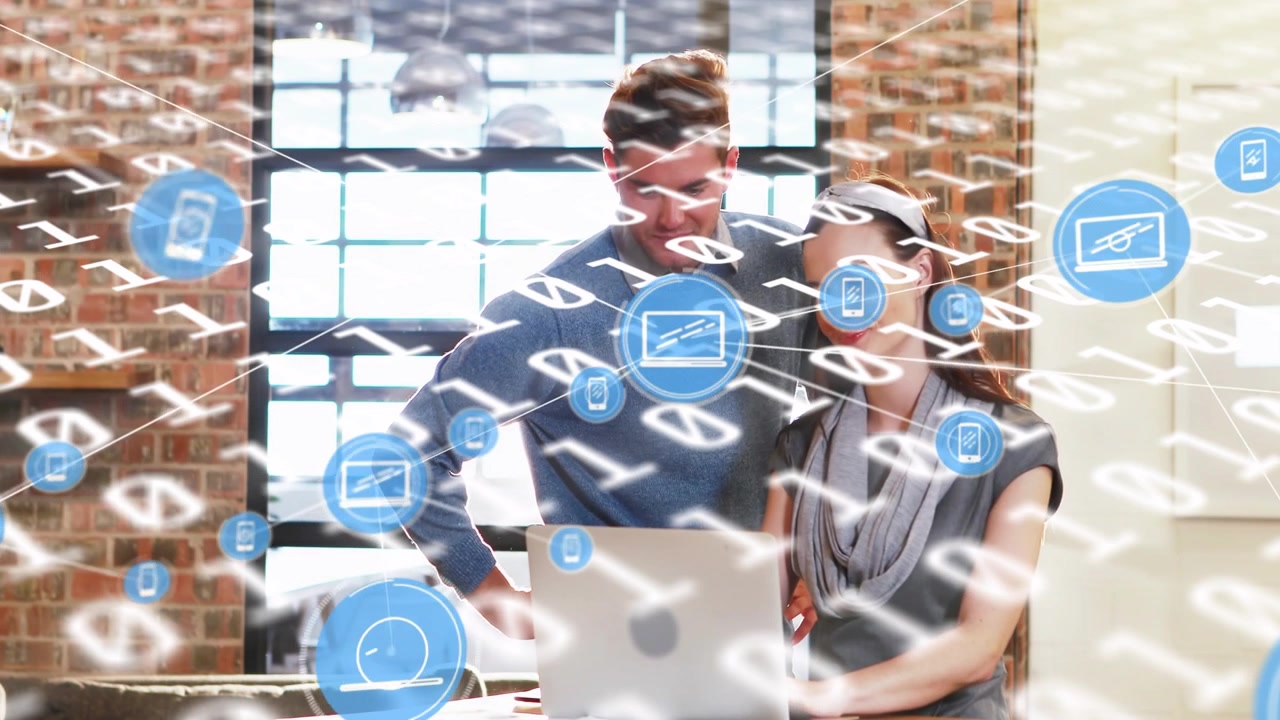 Squadra che gesticola e digita al laptop in un loft, con icone di dispositivi blu animate che mostrano la crescita dei dati tecnologici