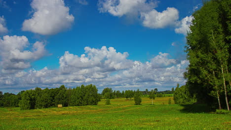 Die-Sonne-Geht-Auf-Und-Lange-Schatten-Verschwinden-Bis-Zur-Baumgrenze,-Während-Weiße,-Flauschige-Wolken-Den-Blauen-Himmel-Füllen