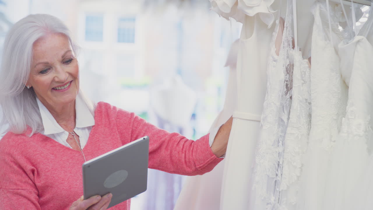 디지털 태블릿과 함께 신부 웨딩 드레스 가게의 고위 여성 소유자