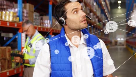 animación de una red de iconos digitales sobre un supervisor caucásico usando una tableta digital en el almacén