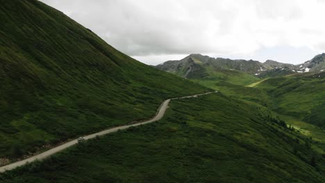 Roadtrip-in-Alaska,-Sunset-and-the-Open-Road,-what-a-view,-following-a-car-down-a-road-from-a-drone