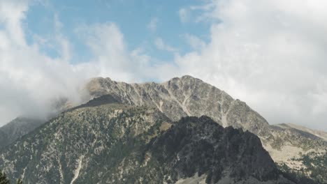 fluffy white clouds passing over the pyrenees mountain peak at daytime in andorra, spain