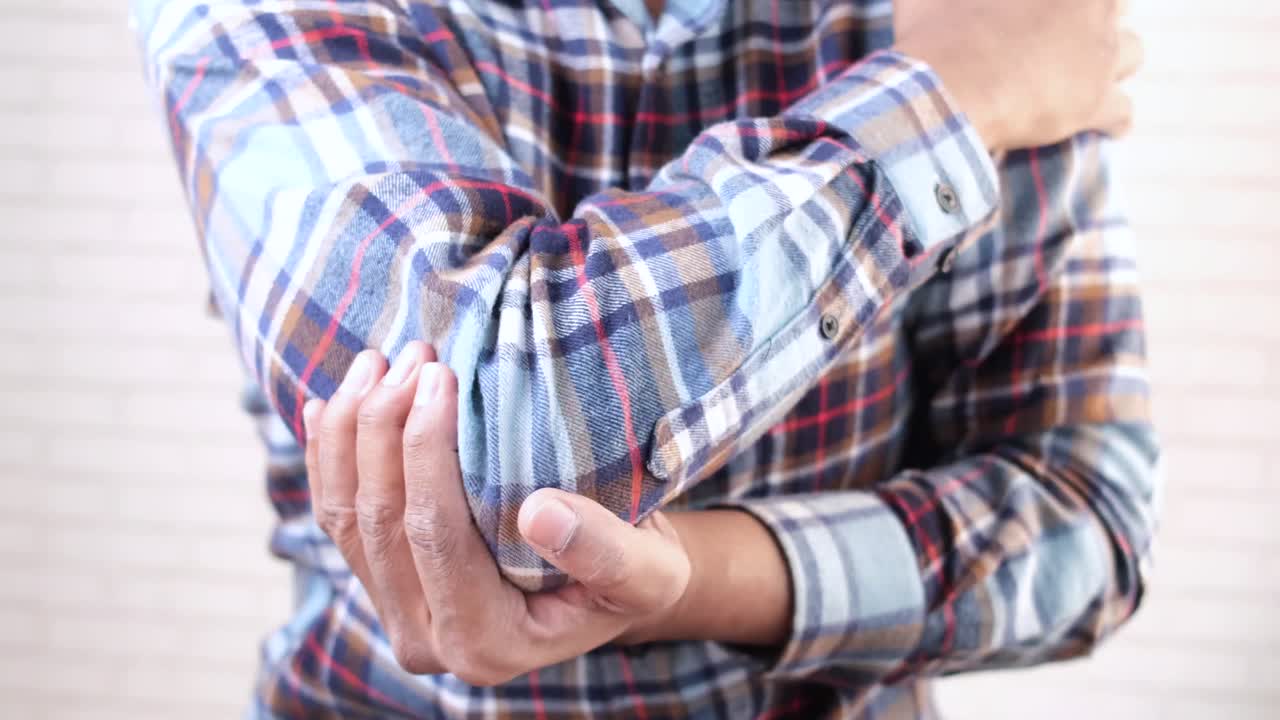 hombre comprobando dolor en el codo