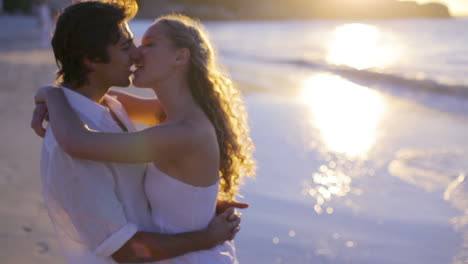 Vista-Lateral-De-Una-Pareja-Besándose-En-La-Playa-Durante-El-Atardecer