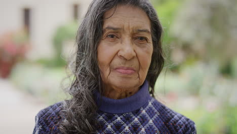 portrait of beautiful elderly indian woman looking serious at camera senior retired female in outdoors background slow motion