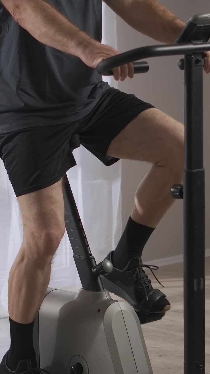 Man's Legs Pedaling a Stationary Bike During a Home Workout