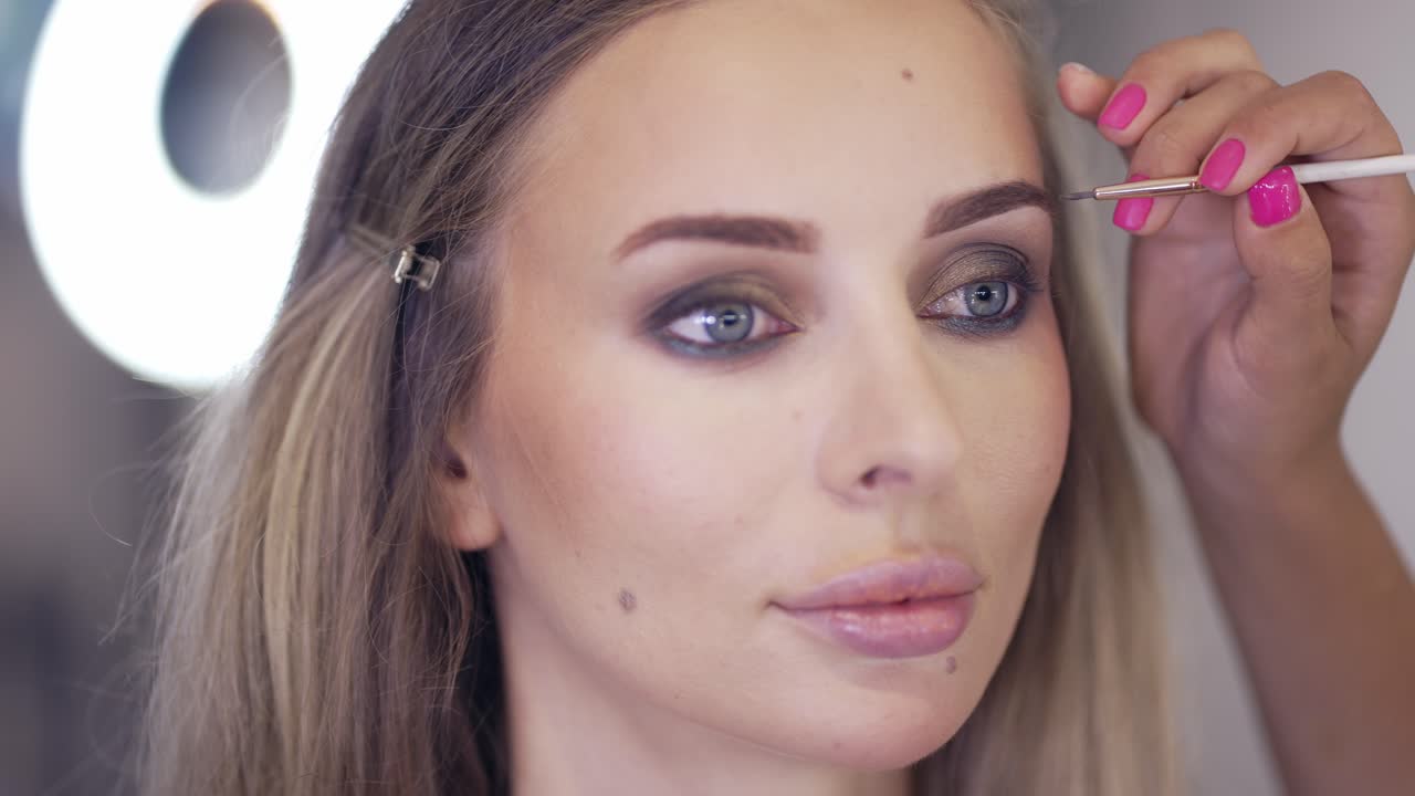 el maquillador pinta las cejas con un pincel, de cerca