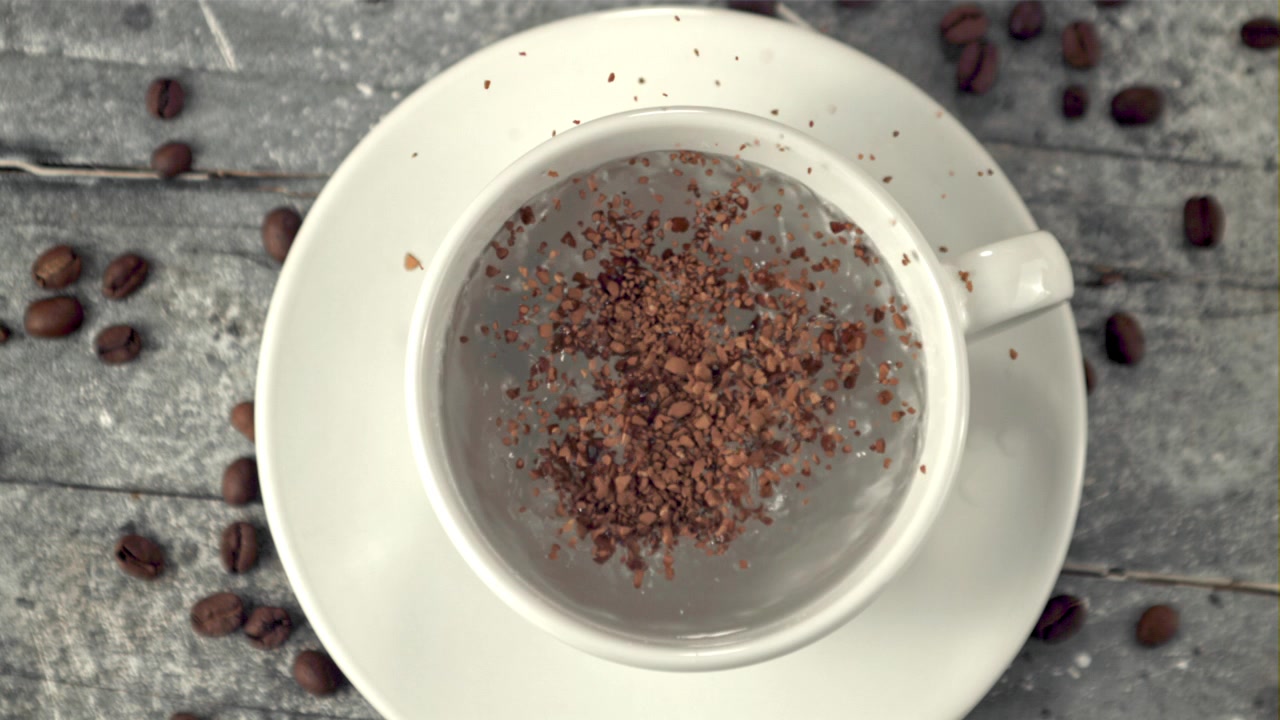 Slow Motion Instant Coffee Granules Falling into a White Cup