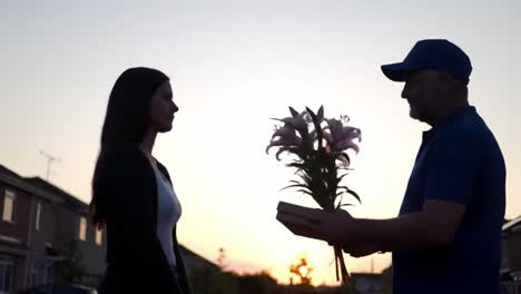 a heartfelt gesture in silhouette: two individuals share an emotional moment at sunset with flowers and connection amidst a beautiful horizon
