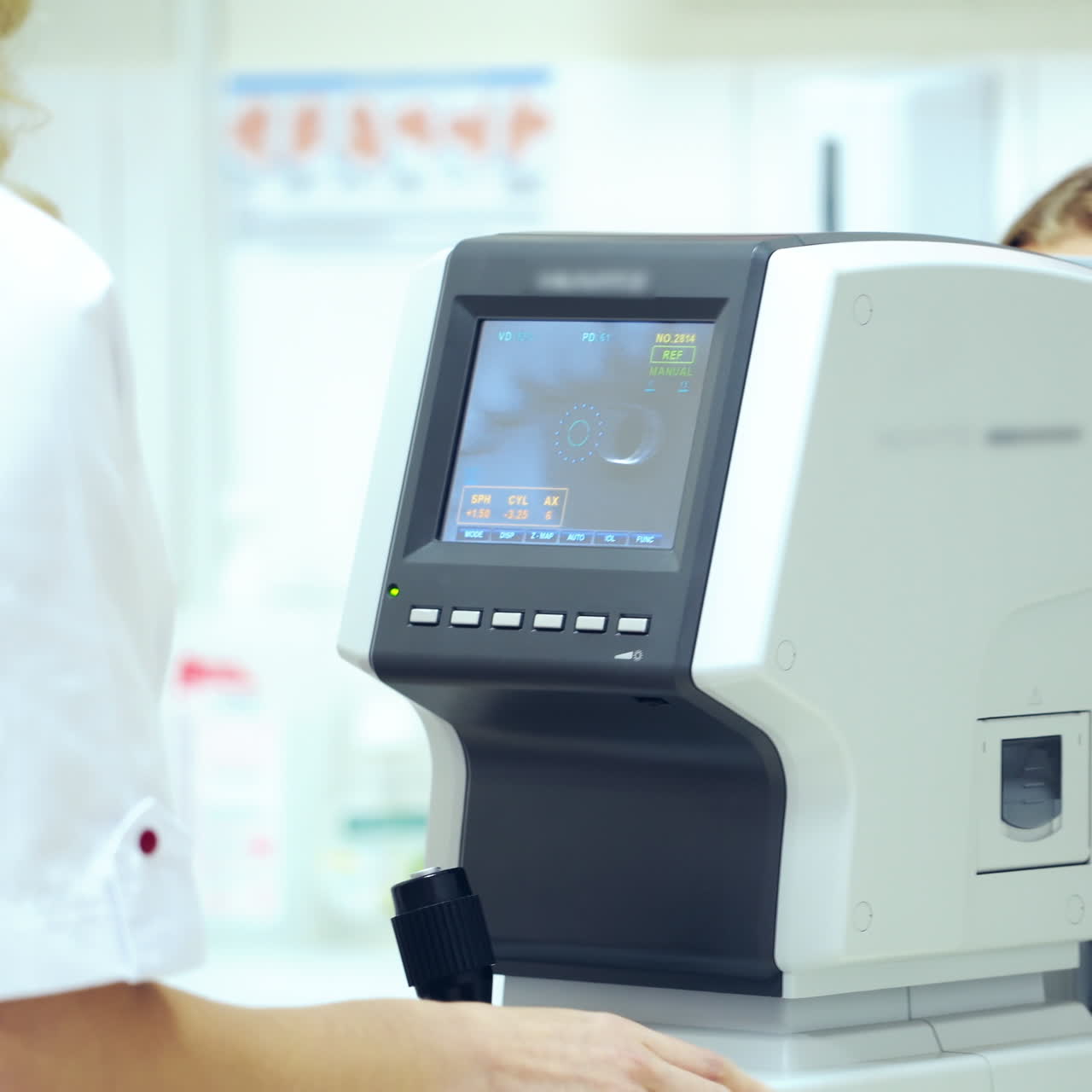 Beautiful woman checking her eyes in clinic. Refractometer tests human eyes and printing the results. Ophthalmologist examines female's eyes on modern device.