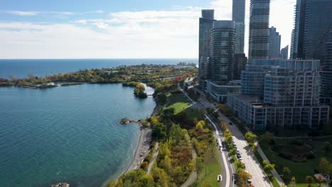 drone flying along the sunny coastline of lake ontario with apartment buildings in toronto