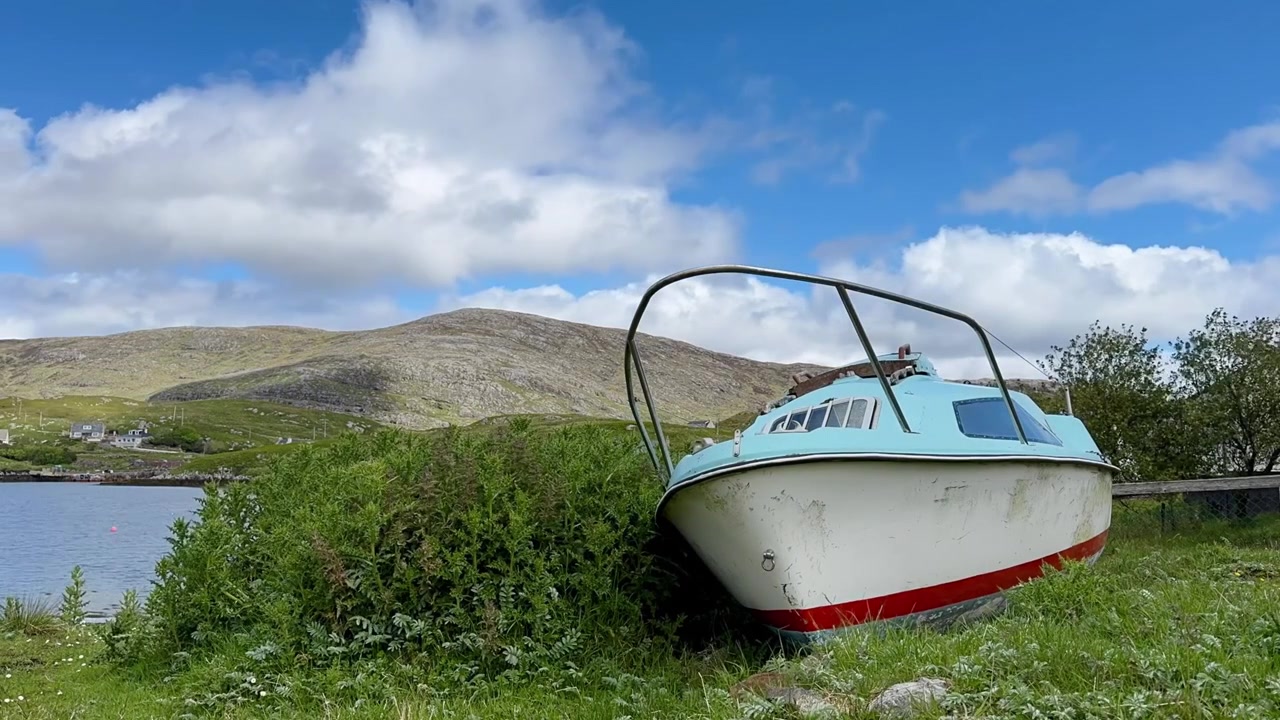 Timelapse-optagelse af en forladt fiskebåd, der hviler på græsland på øen Scalpay i Skotlands Ydre Hebrider. En scene der afspejler maritim arv, isolation og det skiftende vejr.