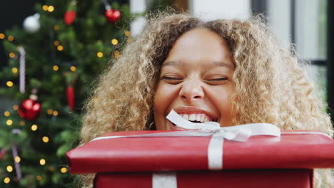 portrait of woman carrying pile of christmas presents standing by tree at home