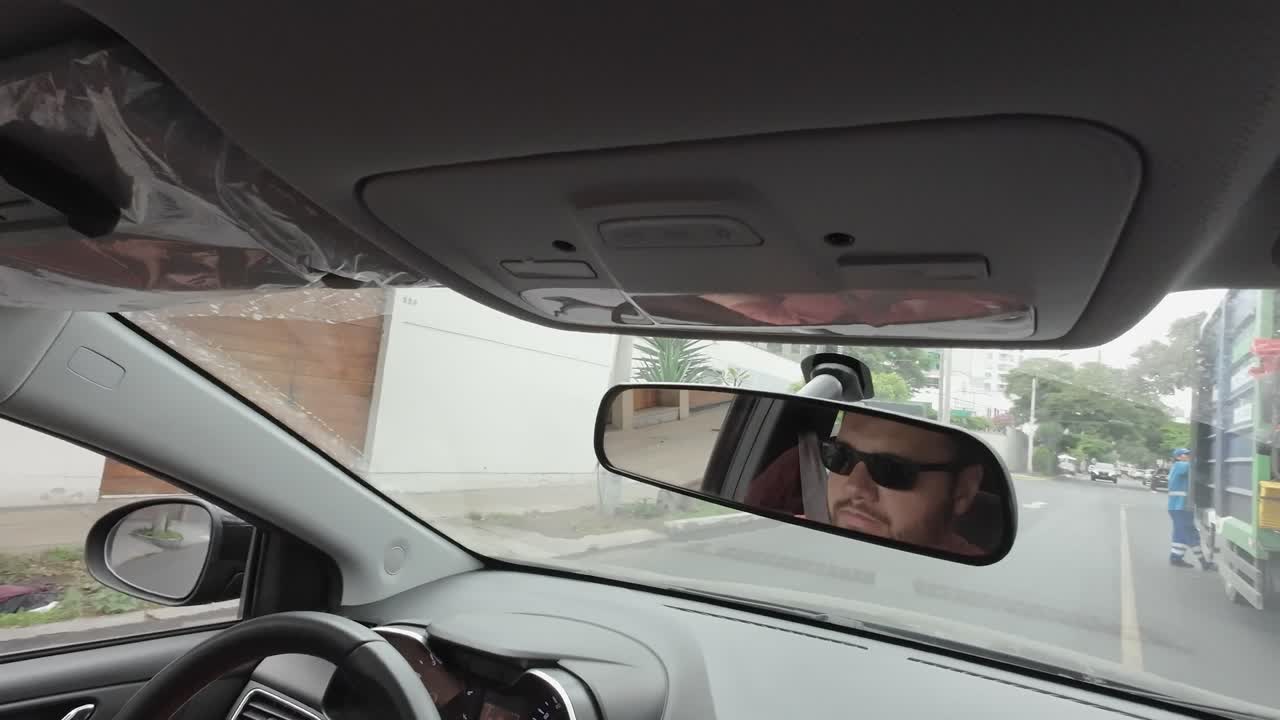 Uomo che guida un'auto riflesso nello specchietto retrovisore