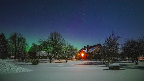 Un-Mágico-Paisaje-Invernal-Muestra-Una-Casa-Y-Un-Jardín-Bajo-La-Nieve-Y,-Al-Fondo,-La-Aurora-Boreal-Con-Un-Cielo-Estrellado-Azul