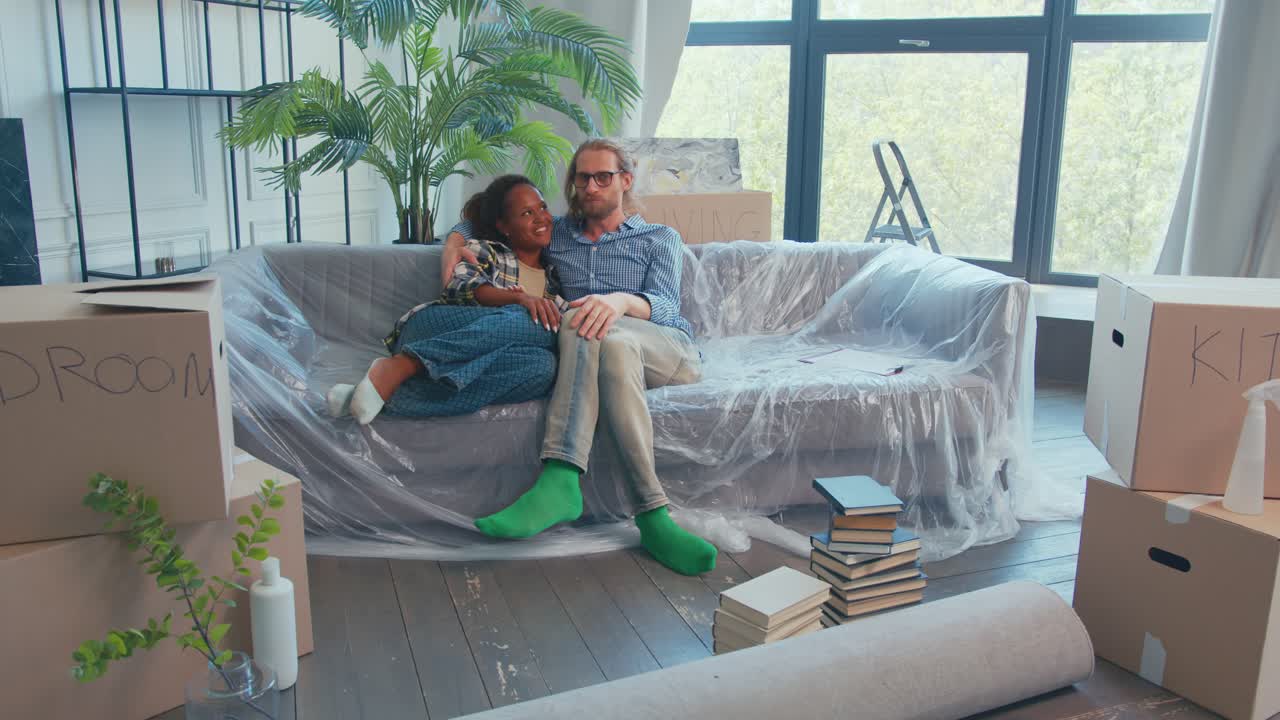 una pareja disfruta de un momento acogedor mientras desembala cajas en su nuevo apartamento.