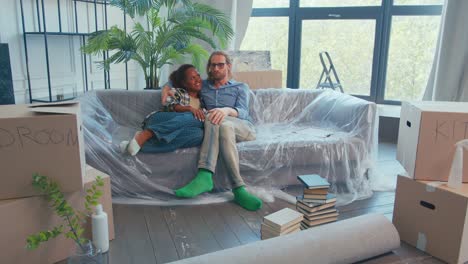 ein paar genießt einen gemütlichen moment, während sie kisten in ihrer neuen wohnung auspacken