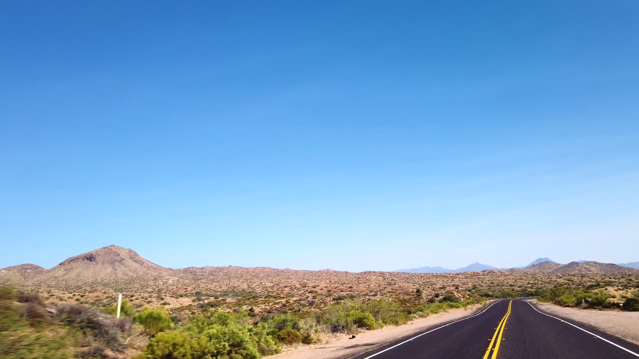 pov conduciendo a través de la tierra plana del desierto de sonora hacia una cordillera distante, scottsdale, arizona