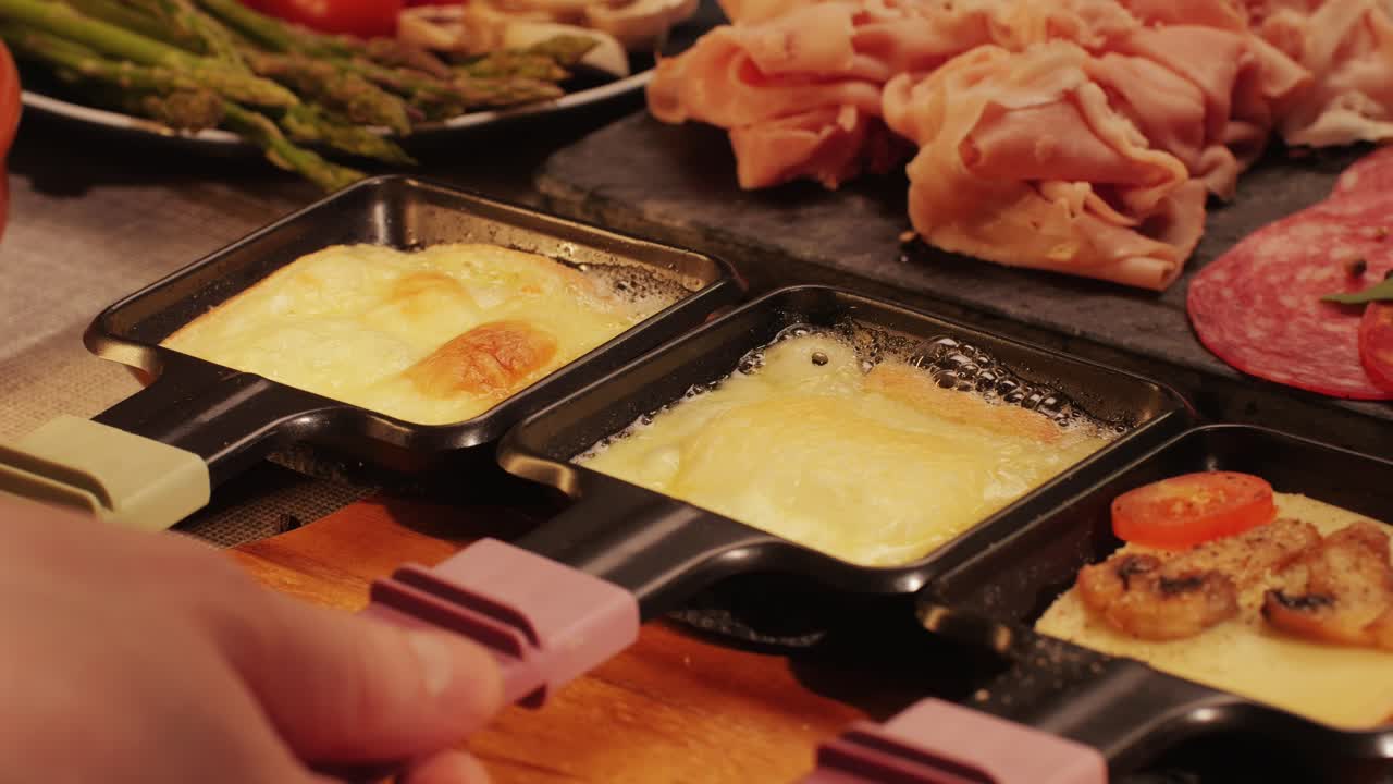 Traditional Swiss melted raclette cheese, hot melted French dish, family cooking dinner with Spanish style tapas ingredients and grill.