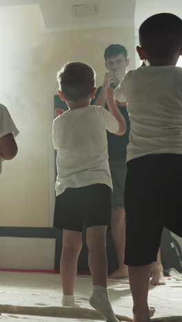 los niños hacen golpes con el instructor en la escuela de boxeo. los pequeños luchadores practican golpes fuertes con un entrenador profesional en el gimnasio a cámara lenta. lección de autodefensa
