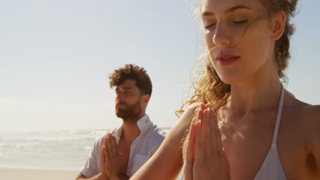 un couple effectuant du yoga sur la plage un jour ensoleillé 4k