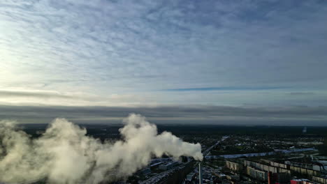 smoke flowing out of a high chimney stack at the industrial area in a city