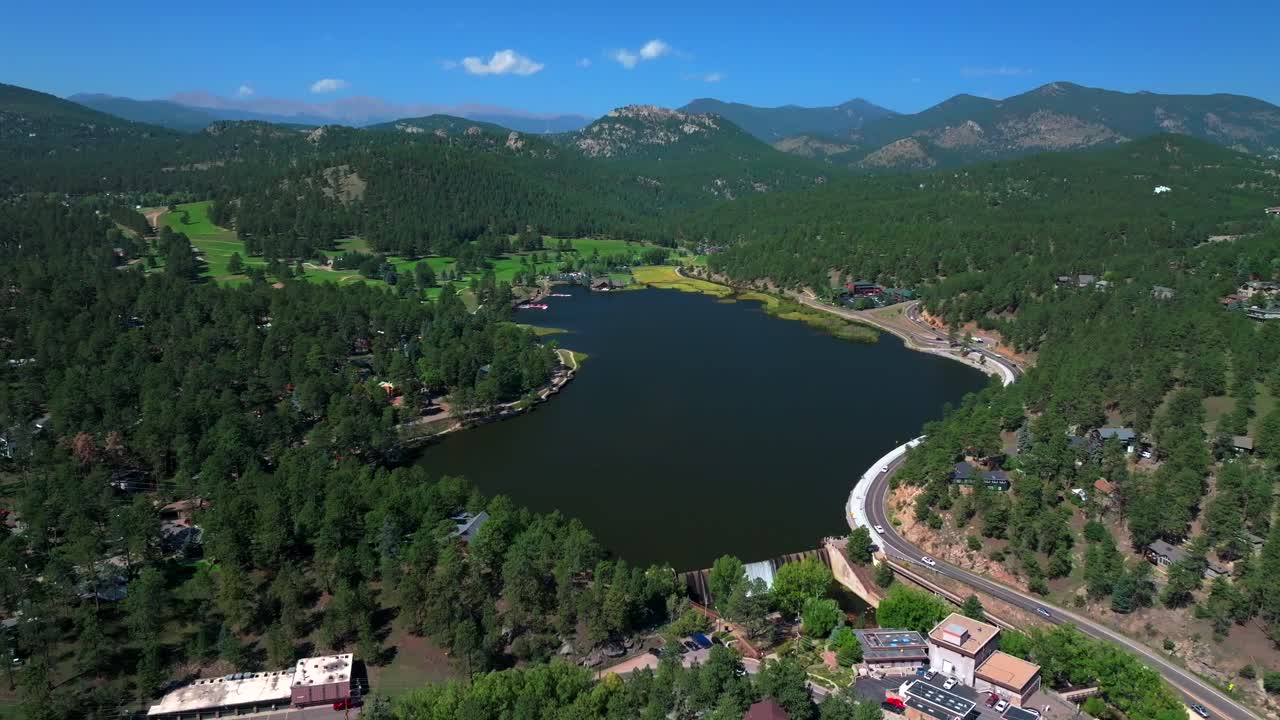 Evergreen Lake House waterfall dam Park and Rec Center Golf Course Keys on the green downtown mountain town summer sunny blue sky flag water dam Colorado aerial drone backwards motion