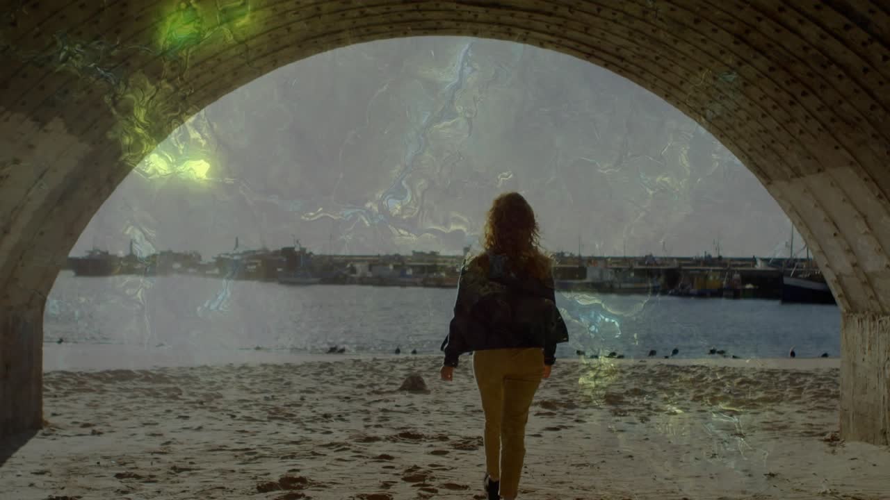 Viaggiatrice che cammina dall'ombra verso una spiaggia illuminata dal sole per vedere la costa, con una sovrapposizione di luce verde che si muove con lei