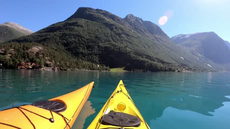 Zwei-Kajaks-Schwimmen-An-Einem-Schönen-Sommertag-Gemeinsam-Am-See-Lovatnet-In-Norwegen-Herum-–-Handaufnahme-Mit-Sonneneruption-Von-Einem-Paar,-Das-Gemeinsam-Paddelt-–-Norwegen