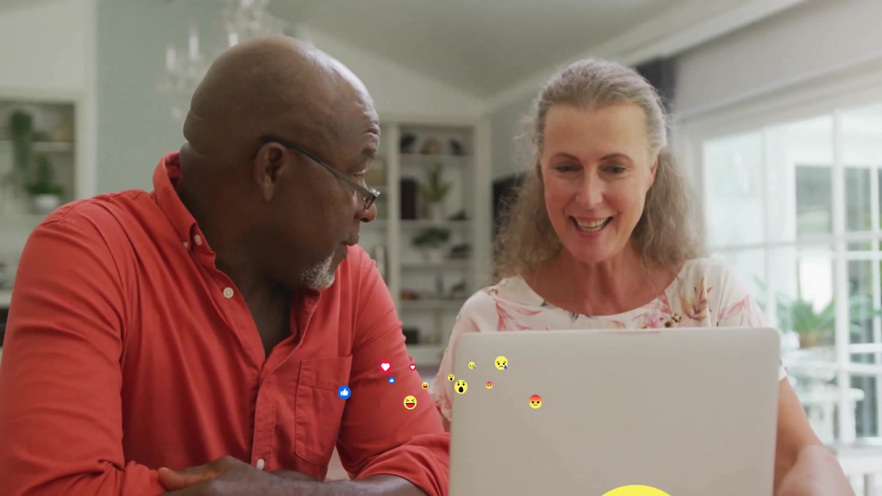 Mature Couple Using Laptop Together at Home with Social Media Emojis