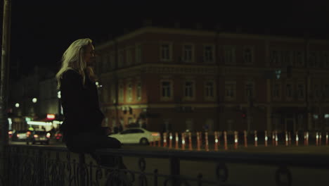 Girl-sitting-bench-night-in-city-lights-enjoying-city-life-in-downtown.