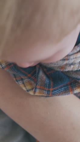 mommy holds adorable little baby wearing warm shirt in arms near woman on light background in room closeup
