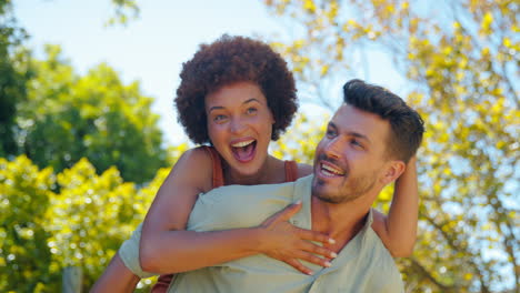 Retrato-De-Una-Amorosa-Pareja-Multirracial-Con-Un-Hombre-Dando-A-Una-Mujer-A-Cuestas-Al-Aire-Libre-En-El-Jardín