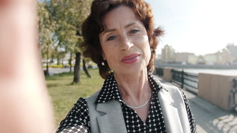 senior woman taking selfie in city park