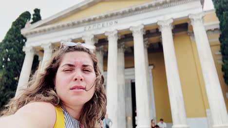 vlogger woman squinting at zappeion hall in bright athens sun