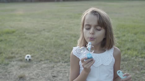 chica caucásica soplando burbujas con los ojos cerrados en el parque