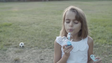 caucasian girl blowing bubbles with closed eyes in the park