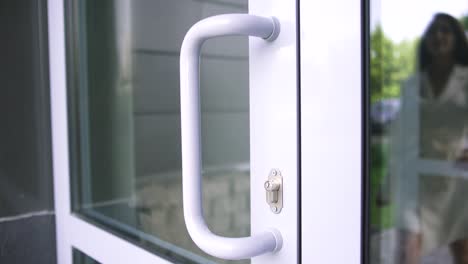 mujer abriendo una puerta de vidrio moderna