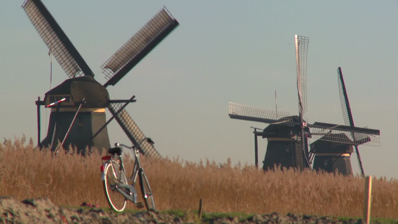 велосипед припаркован на тропинке в голландии, на заднем плане - ветряные мельницы