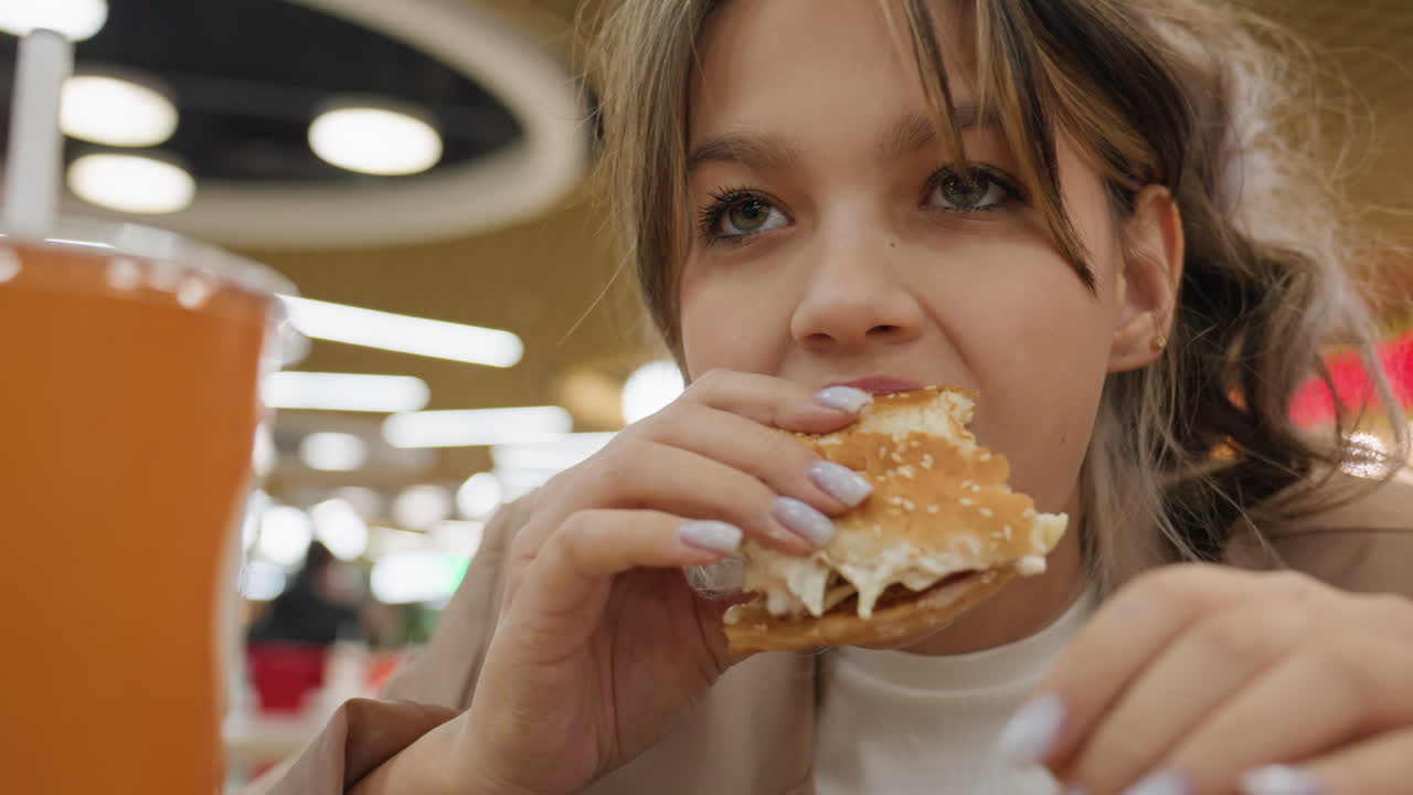 Дегустатор европеоидной расы рассматривает сэндвич перед тем, как откусить, внимательно изучает начинку, рядом с тарелкой — оранжевая чашка, мягкий верхний свет, повседневный пиджак, крупный план руки, момент подготовки к дегустации