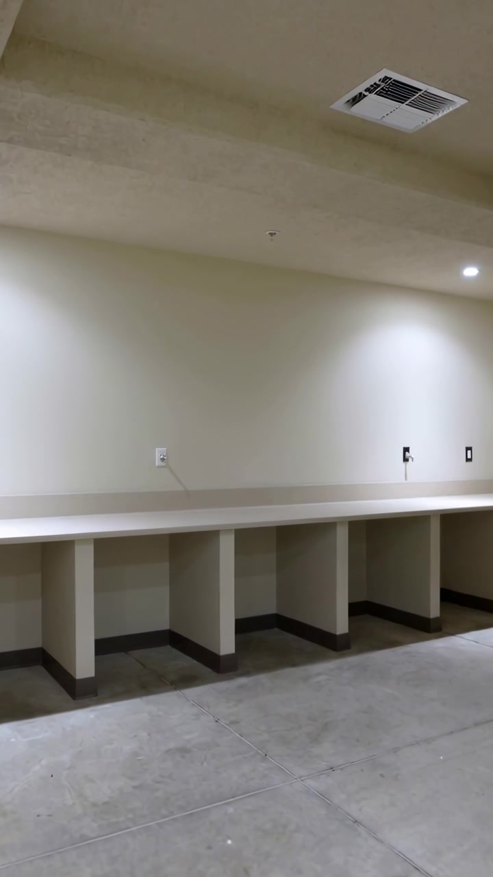 Vertical video: Panning camera scanning counter with cubbies in basement to show outlets, vent