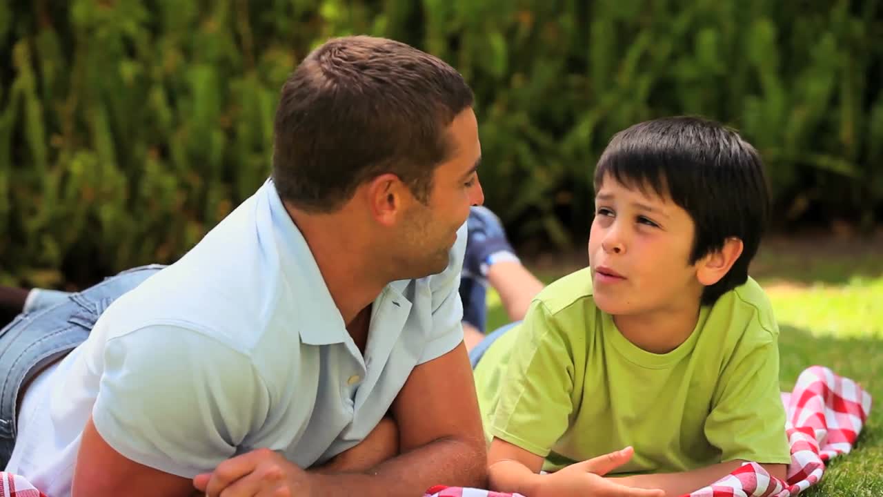 padre e hijo acostados charlando al aire libre